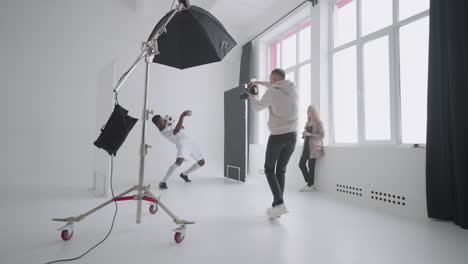afro-american-footballer-is-playing-with-ball-and-posing-for-photographer-during-shooting-for-magazine